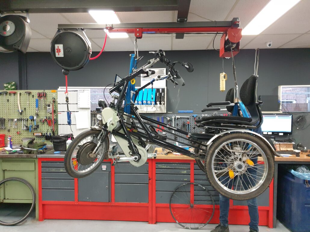 De duofiets hangt aan banden in de werkplaats van fietsenmaker Coen.